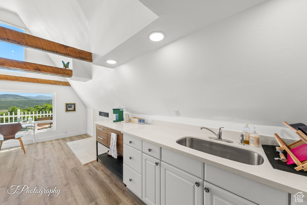 Kitchen featuring white cabinetry, light wood-type flooring, lofted ceiling, light countertops, and recessed lighting