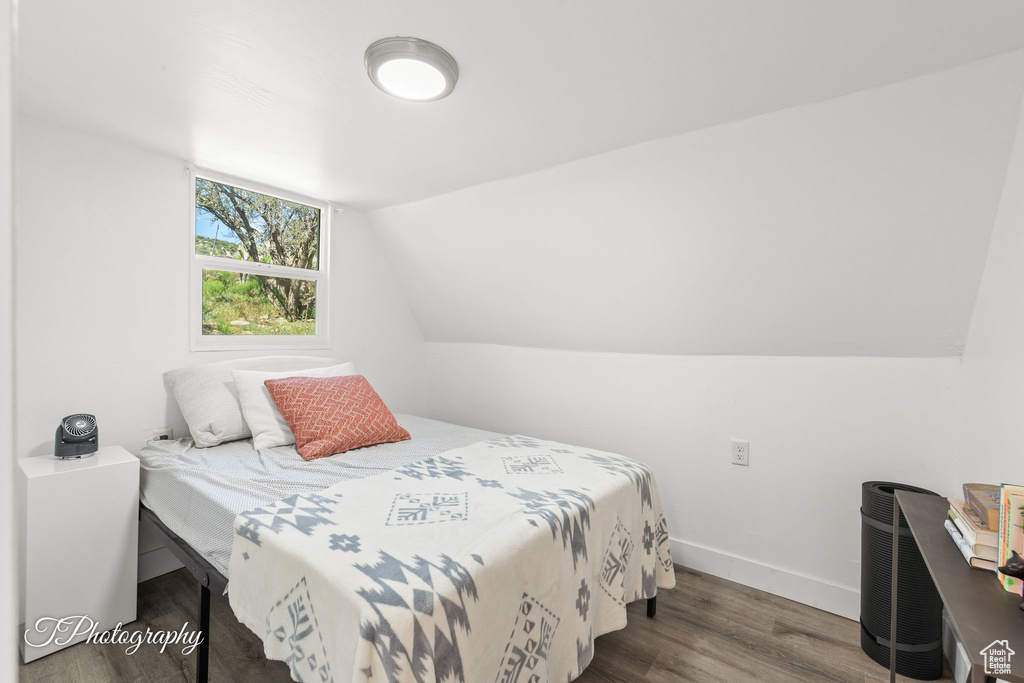 Bedroom featuring wood finished floors and lofted ceiling