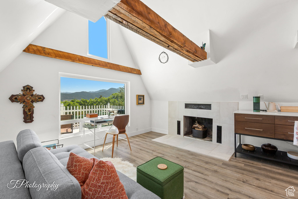 Living area with light wood-style floors, a tiled fireplace, and a mountain view