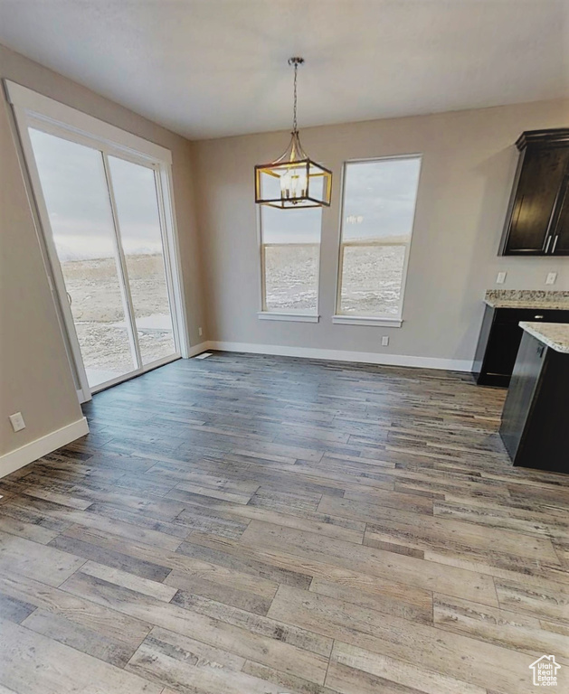Unfurnished dining area with wood finished floors and a chandelier