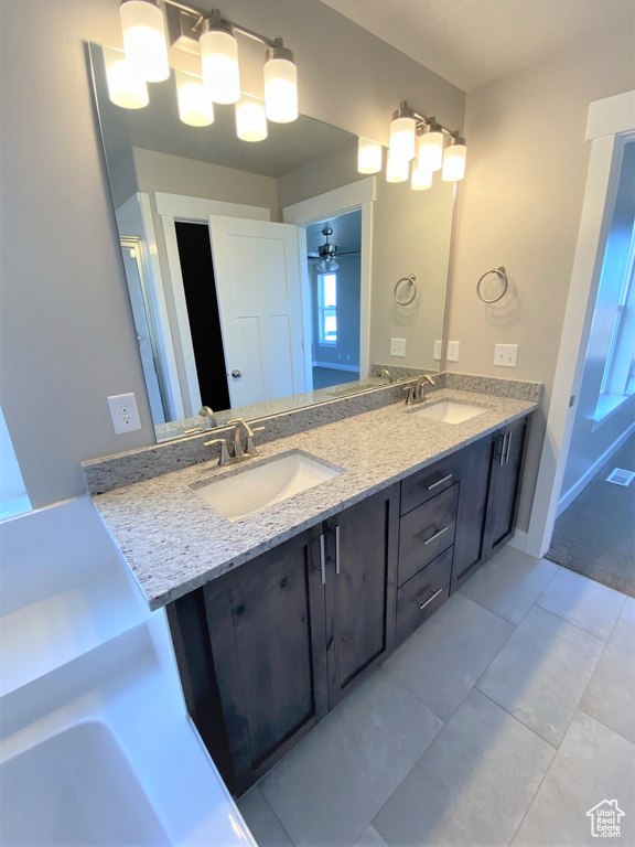 Bathroom featuring double vanity, tile patterned floors, and a bath