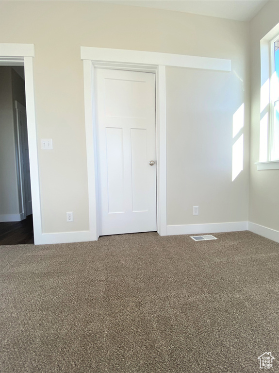 Empty room featuring dark carpet and baseboards