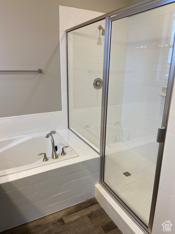 Bathroom with a stall shower, a bath, and wood finished floors