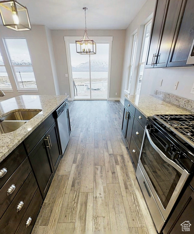 Kitchen with stainless steel appliances, light wood-style flooring, healthy amount of natural light, and decorative light fixtures