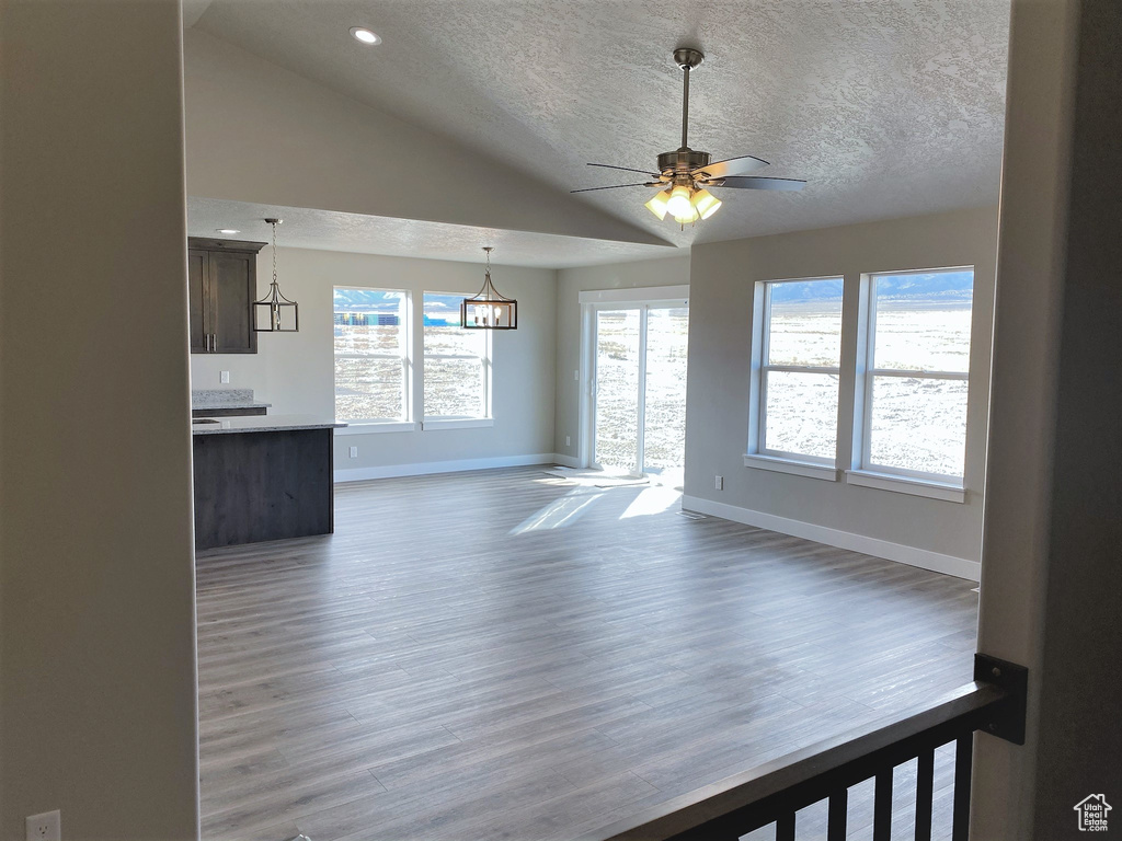 Unfurnished living room with a textured ceiling, light wood finished floors, ceiling fan, recessed lighting, and lofted ceiling