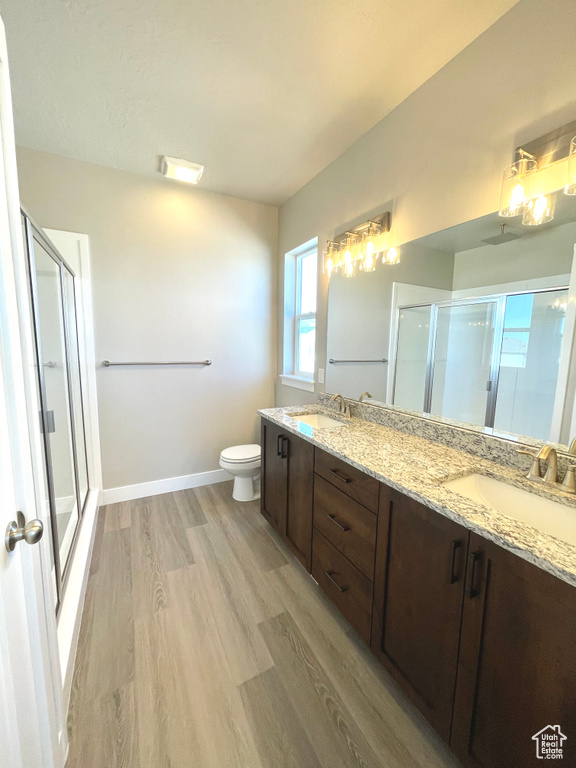 Bathroom featuring a stall shower, double vanity, and wood finished floors