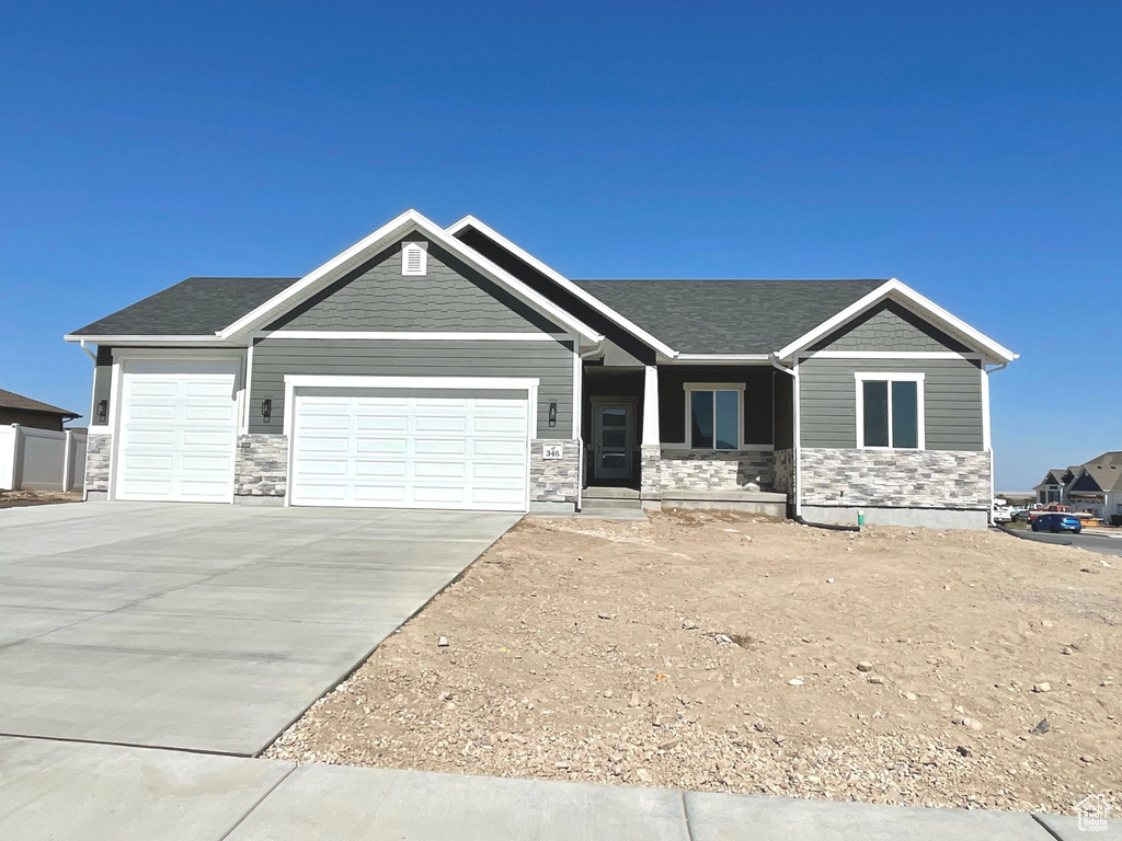 Craftsman-style home with an attached garage, concrete driveway, and stone siding