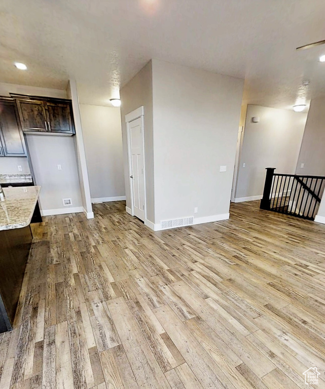 Unfurnished living room featuring light wood finished floors and baseboards