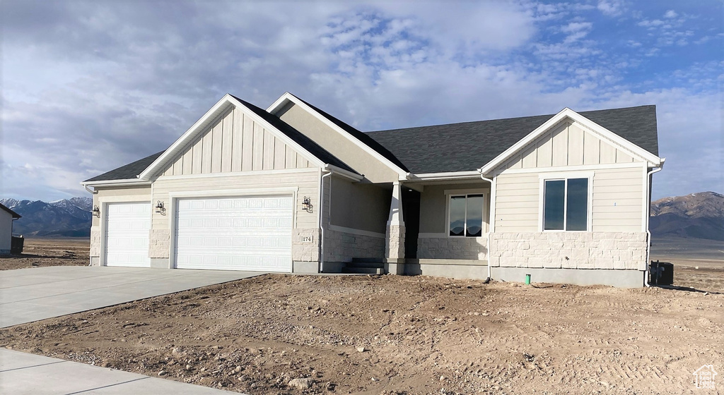 View of front of property with board and batten siding, an attached garage, concrete driveway, and a mountain view