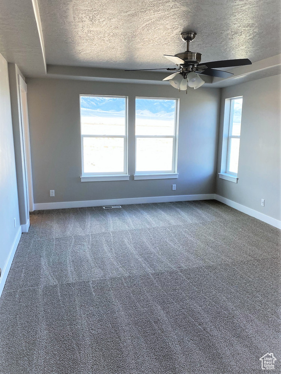 Empty room with a textured ceiling, carpet, and ceiling fan