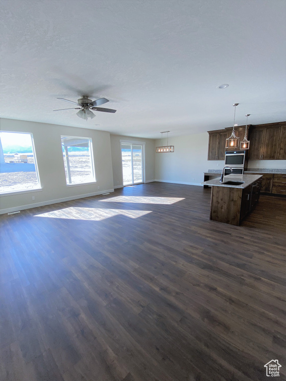 Unfurnished living room with dark wood finished floors and a ceiling fan