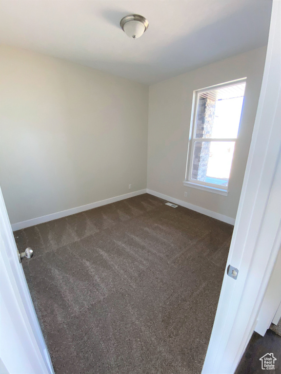 Spare room with dark colored carpet and baseboards