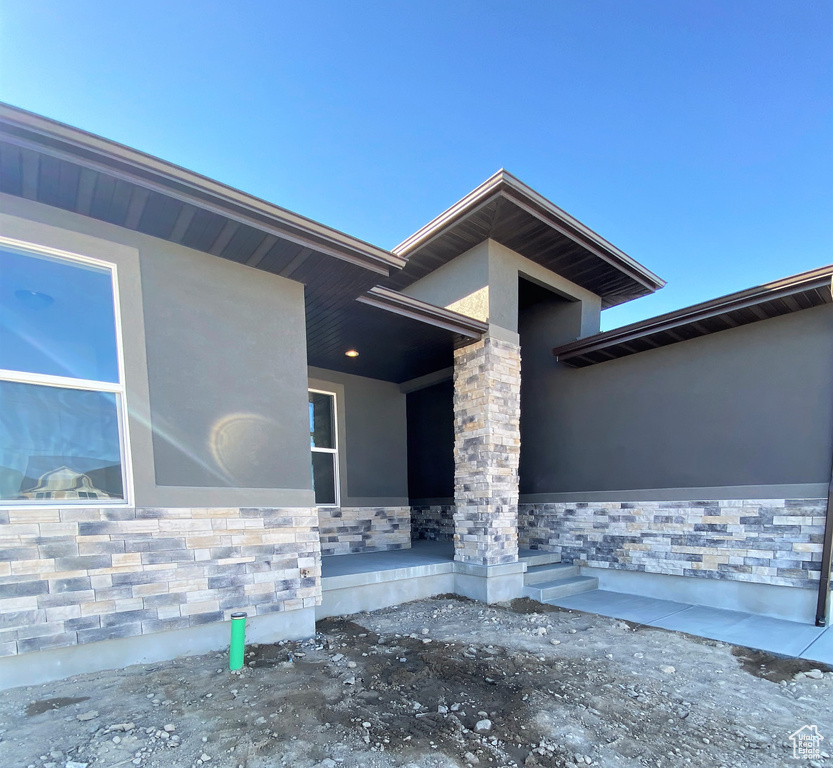 Doorway to property with stucco siding and stone siding