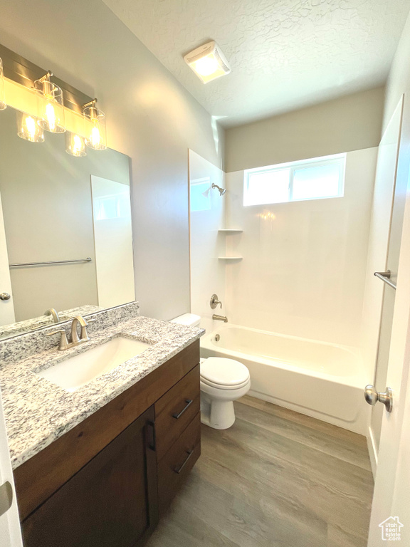 Bathroom featuring vanity, wood finished floors, a textured ceiling, and bathing tub / shower combination