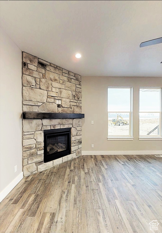 Unfurnished living room featuring a stone fireplace and wood finished floors