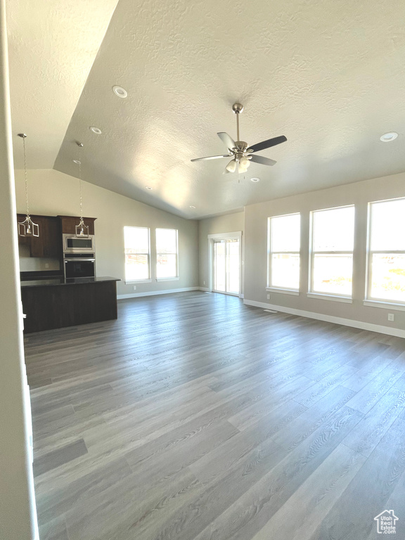 Unfurnished living room with lofted ceiling, wood finished floors, a textured ceiling, a ceiling fan, and recessed lighting
