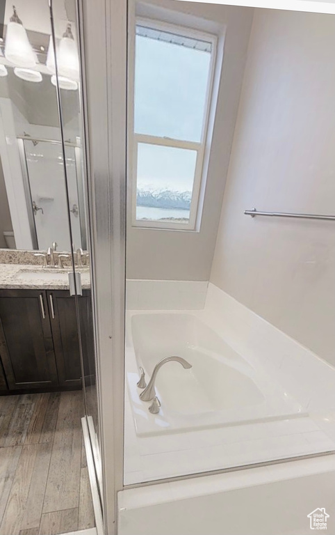 Bathroom with a stall shower, vanity, a bath, and wood finished floors