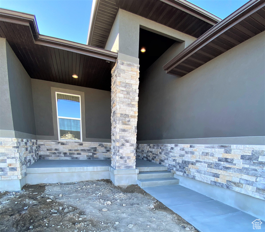 Entrance to property with stucco siding and stone siding