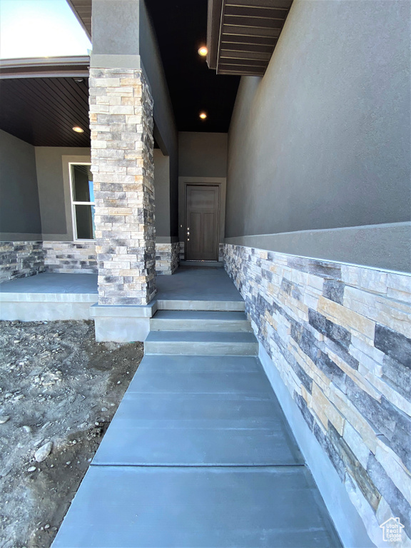 Doorway to property with stucco siding and stone siding