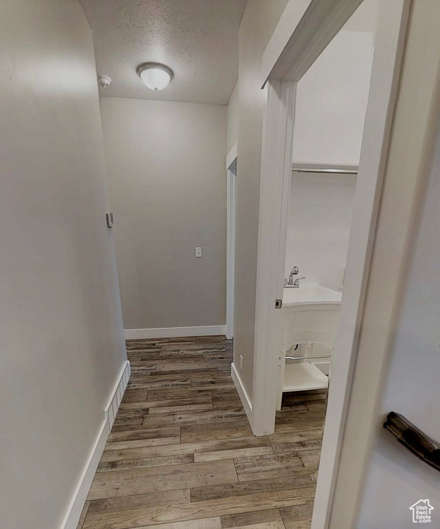 Hallway with a textured ceiling and wood finished floors