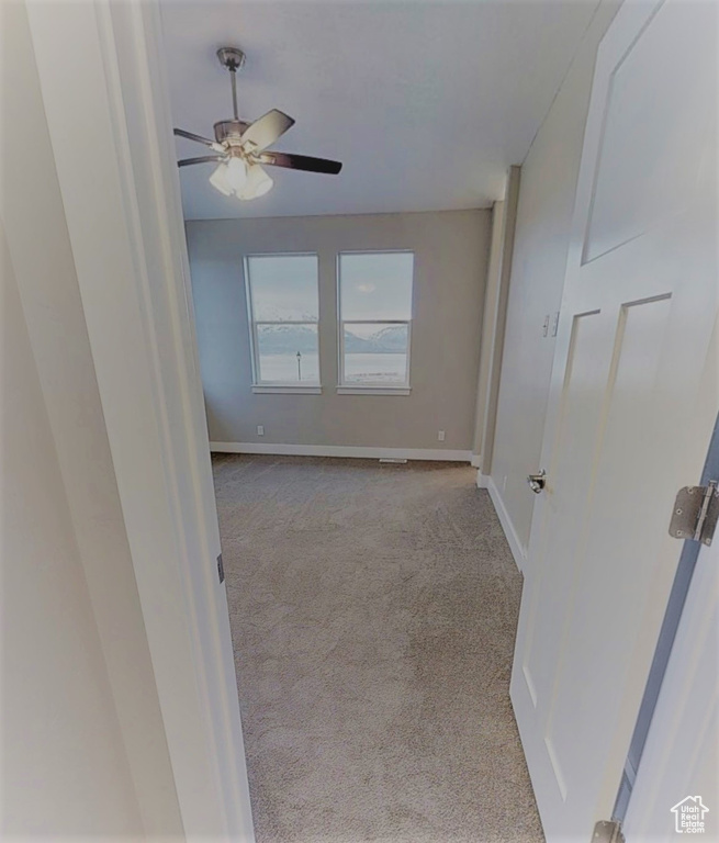 Carpeted spare room featuring ceiling fan and baseboards