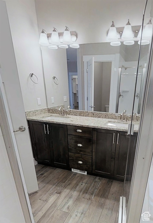 Bathroom featuring wood finished floors, double vanity, and a shower stall