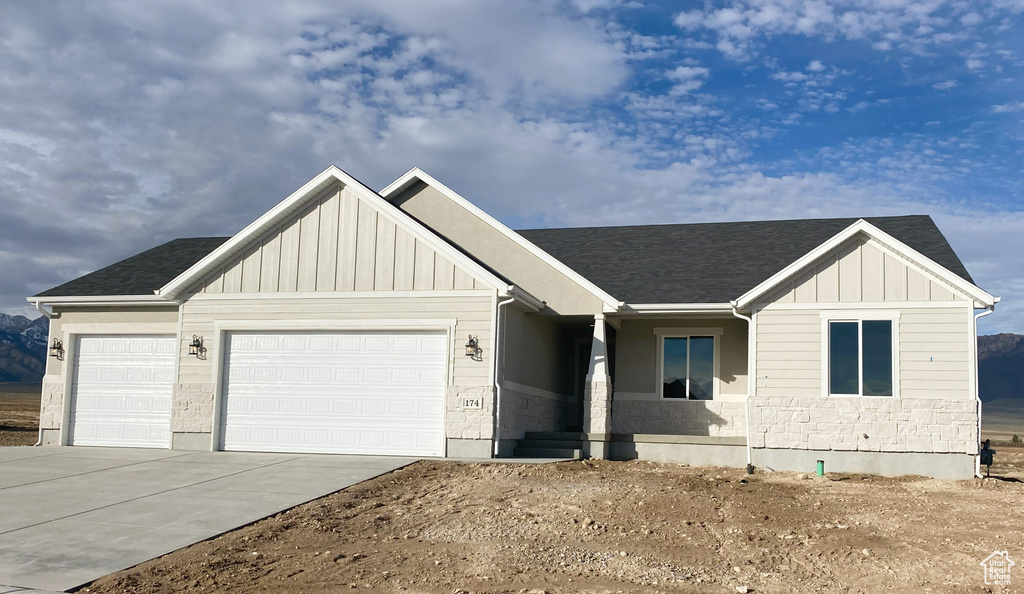 View of front of home featuring board and batten siding, an attached garage, driveway, and a shingled roof
