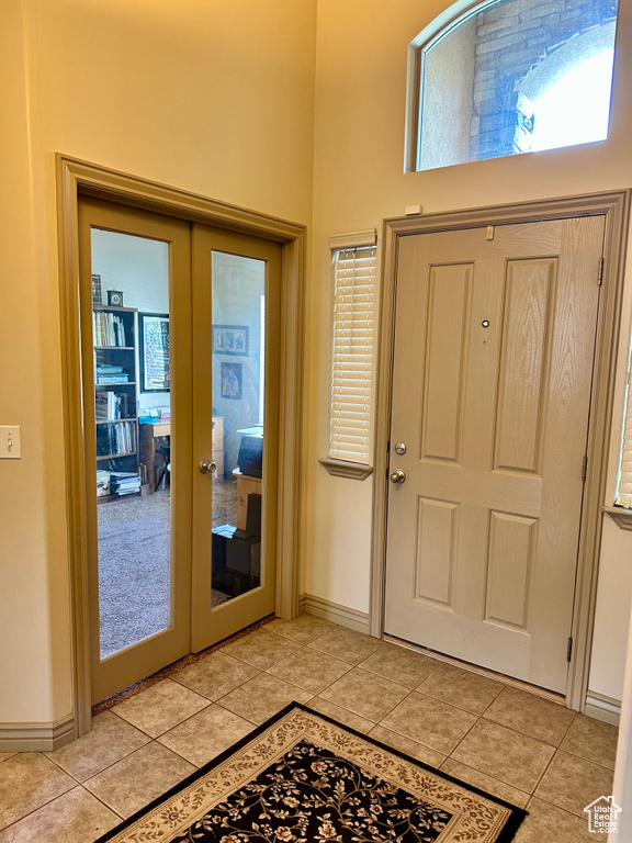 Entryway with french doors, light tile patterned floors, and a towering ceiling
