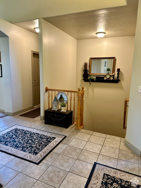 Hallway with an upstairs landing, tile patterned floors, and a textured ceiling