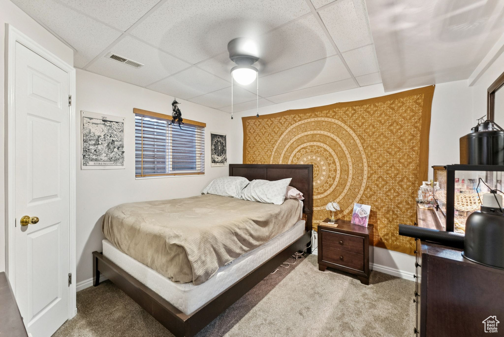 Carpeted bedroom featuring a paneled ceiling and a ceiling fan