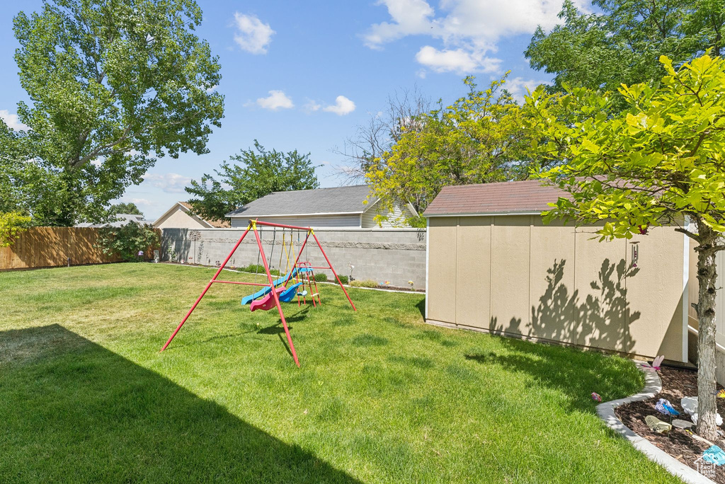 Fenced backyard featuring a shed and a playground