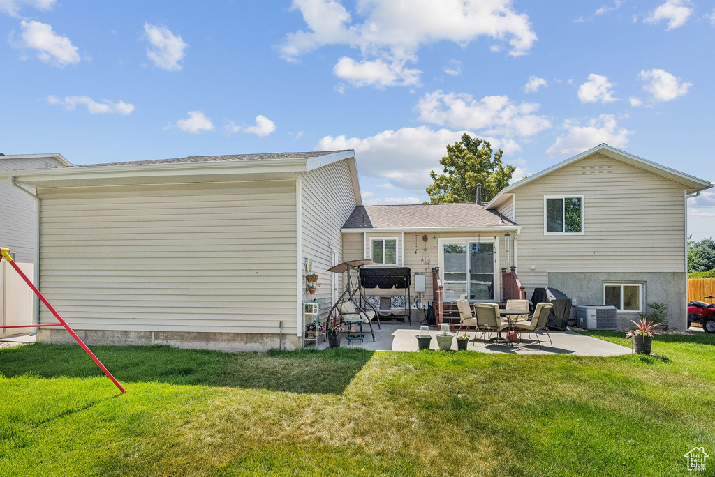 Rear view of house with a patio and a lawn