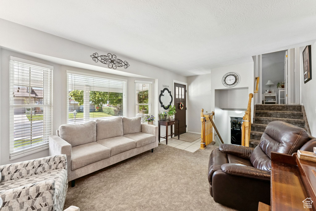 Tiled living area with stairway, carpet floors, and a textured ceiling