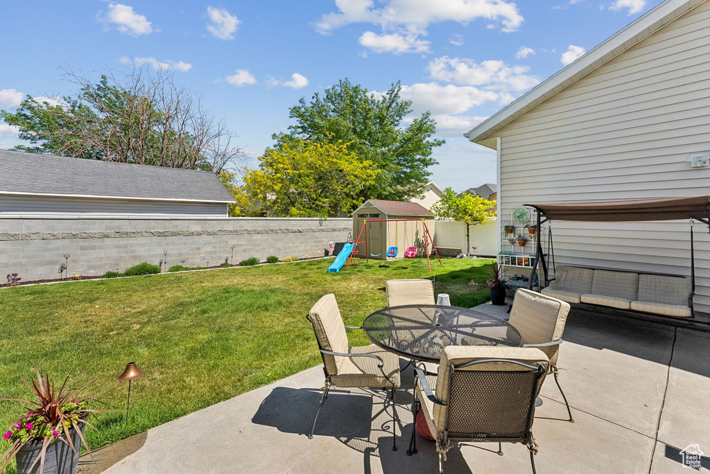 Fenced backyard featuring a patio, outdoor dining area, and a playground