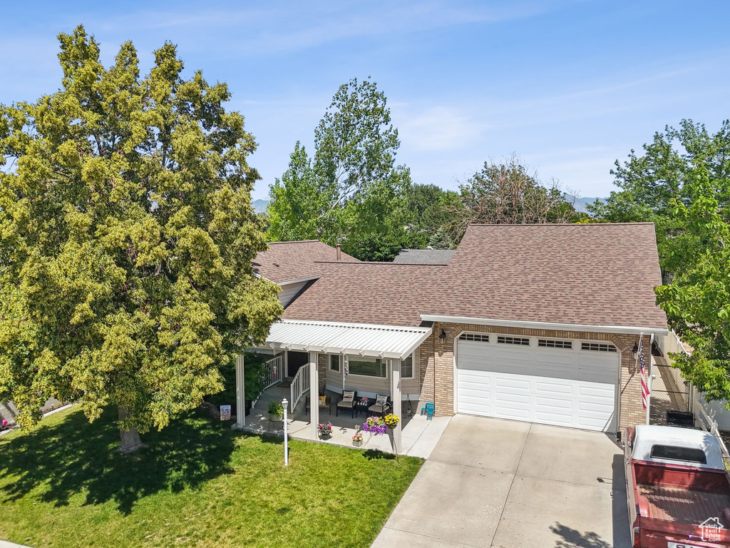 View of front of home featuring roof with shingles, a front yard, a garage, driveway, and brick siding