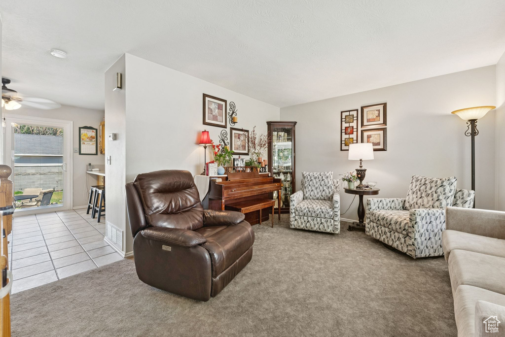 Living room featuring ceiling fan, carpet flooring, and tile patterned flooring