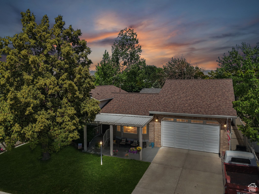 View of front of property with roof with shingles, a garage, a front lawn, and driveway
