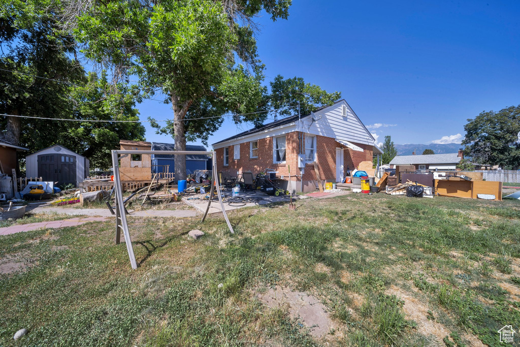 Rear view of house featuring a shed, a yard, and brick siding