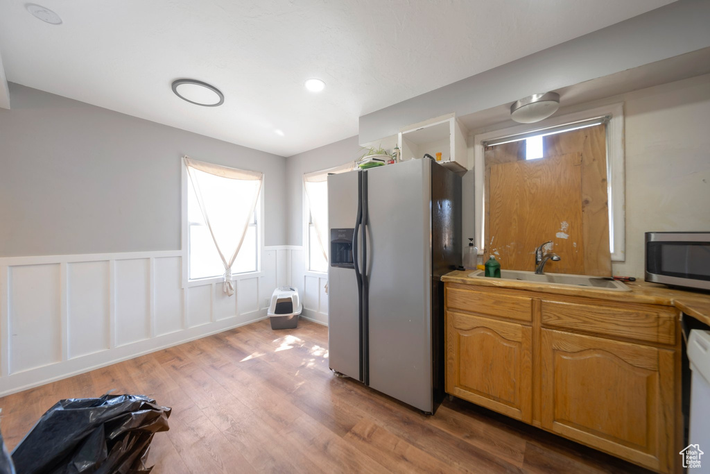 Kitchen featuring appliances with stainless steel finishes, a wainscoted wall, wood finished floors, and light countertops