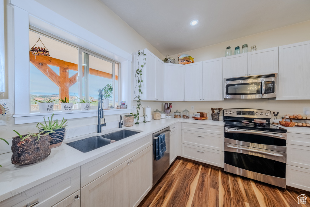 Kitchen with appliances with stainless steel finishes, light countertops, dark wood-type flooring, white cabinets, and recessed lighting