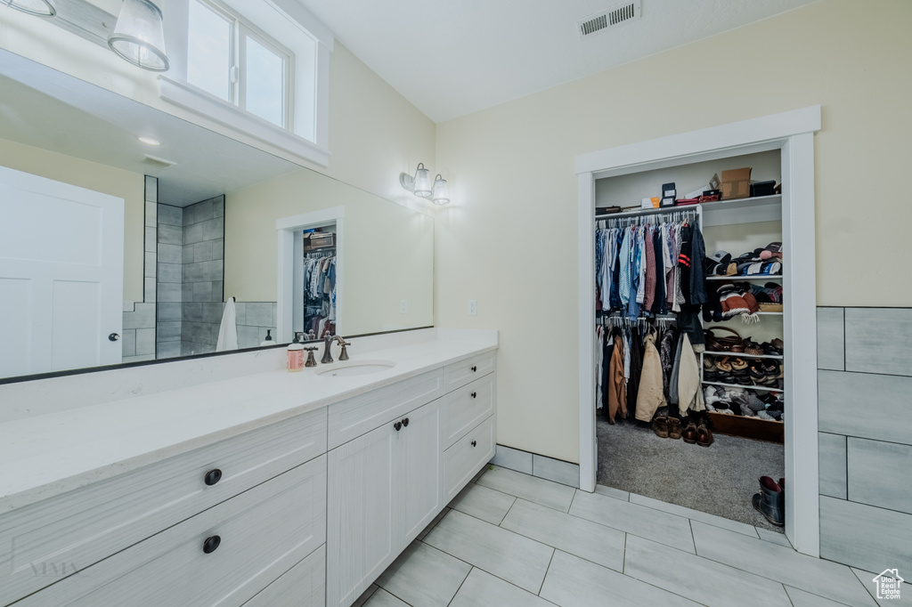 Full bathroom with vanity, a spacious closet, and tile patterned floors
