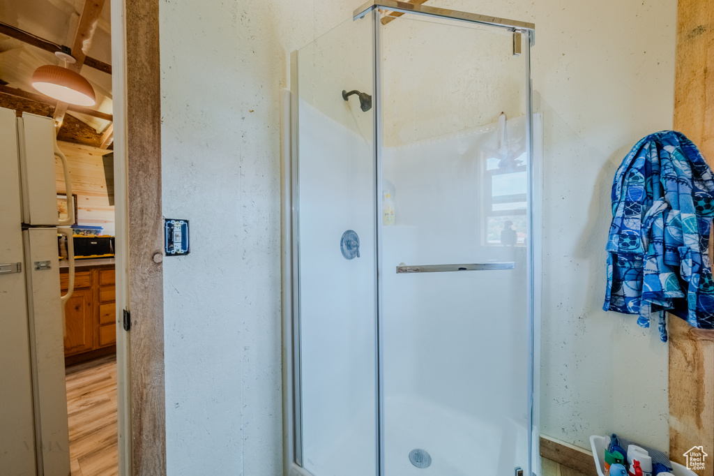 Full bath with a shower stall and wood finished floors