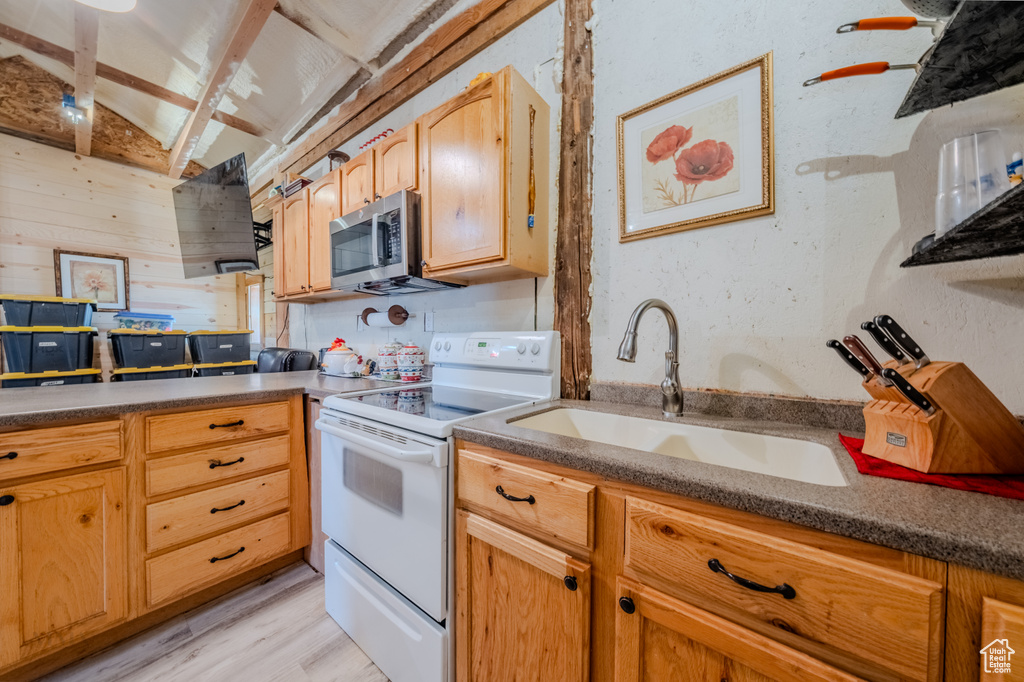 Kitchen featuring white electric range, stainless steel microwave, light wood-type flooring, and dark countertops