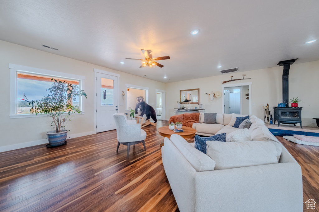 Living area featuring a wood stove, wood finished floors, recessed lighting, a ceiling fan, and healthy amount of natural light