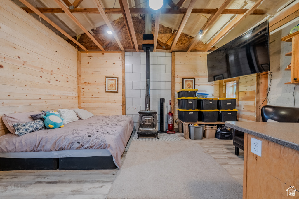 Bedroom featuring wood walls, a wood stove, and carpet floors