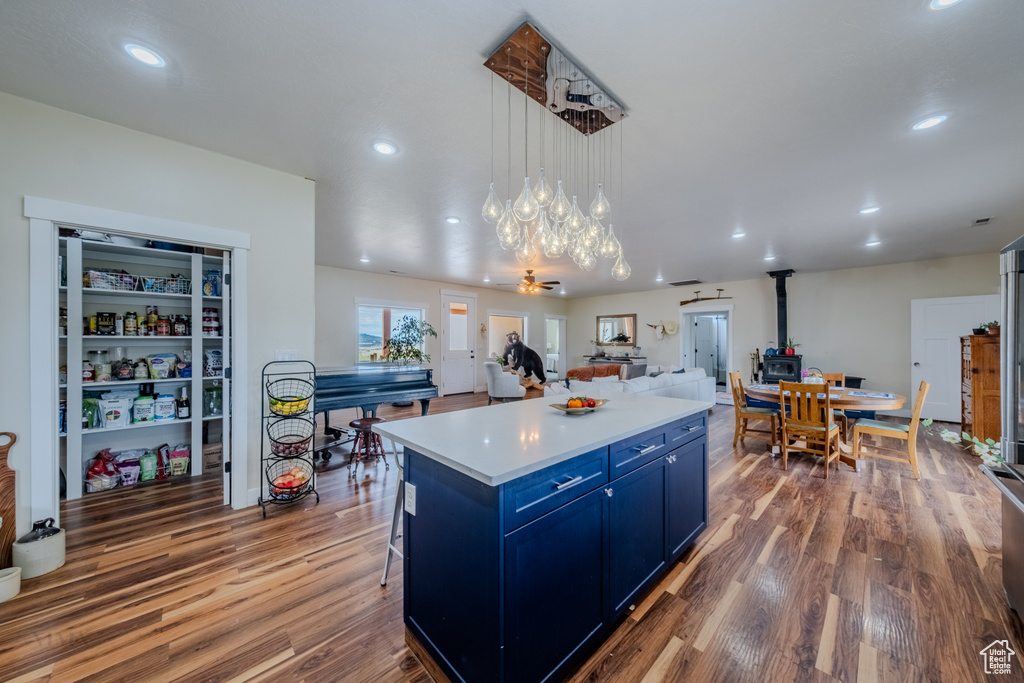 Kitchen featuring blue cabinetry, a wood stove, wood finished floors, light countertops, and recessed lighting