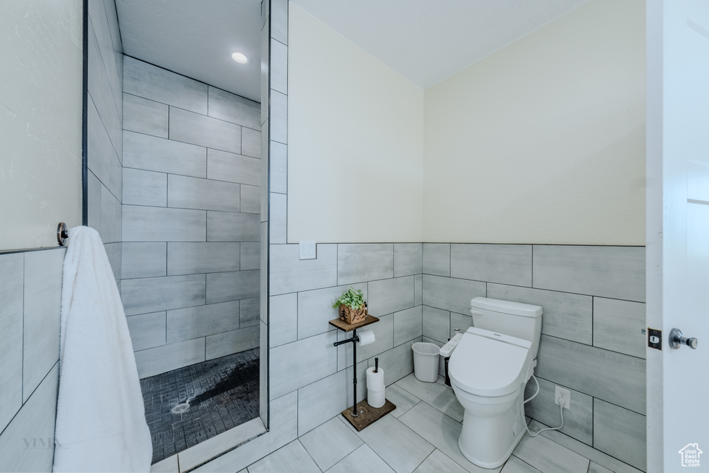 Bathroom with tile walls, tiled shower, tile patterned flooring, and wainscoting