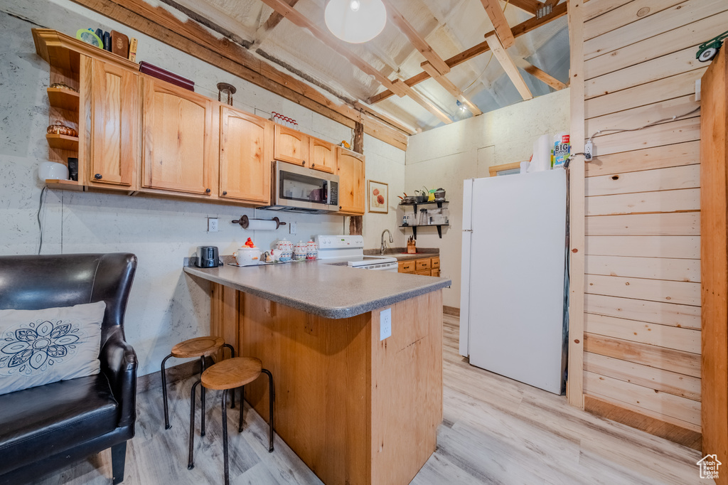 Kitchen with white appliances, light wood-style floors, a peninsula, and open shelves