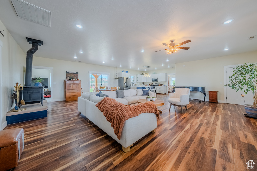 Living room with wood finished floors, ceiling fan, a wood stove, and recessed lighting