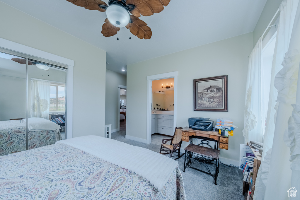Bedroom featuring a closet, light carpet, ensuite bathroom, and ceiling fan